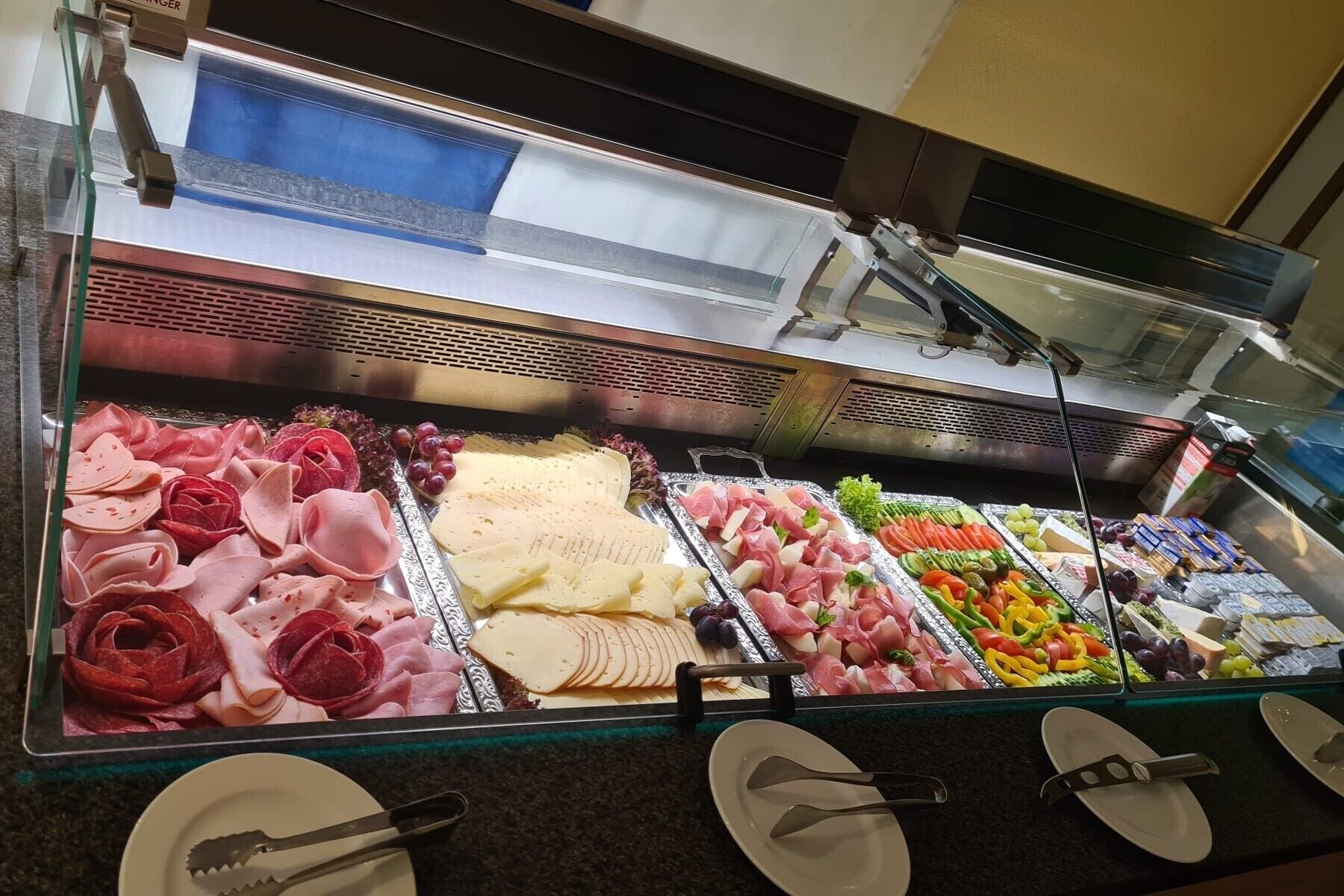 Eine Bedientheke mit verschiedenen Fleisch-, Käse- und Obstsorten.