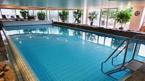 An indoor swimming pool with clear water, tiled floor, and a stone border. - Sport Hotel Kenzingen (Kenzingen)