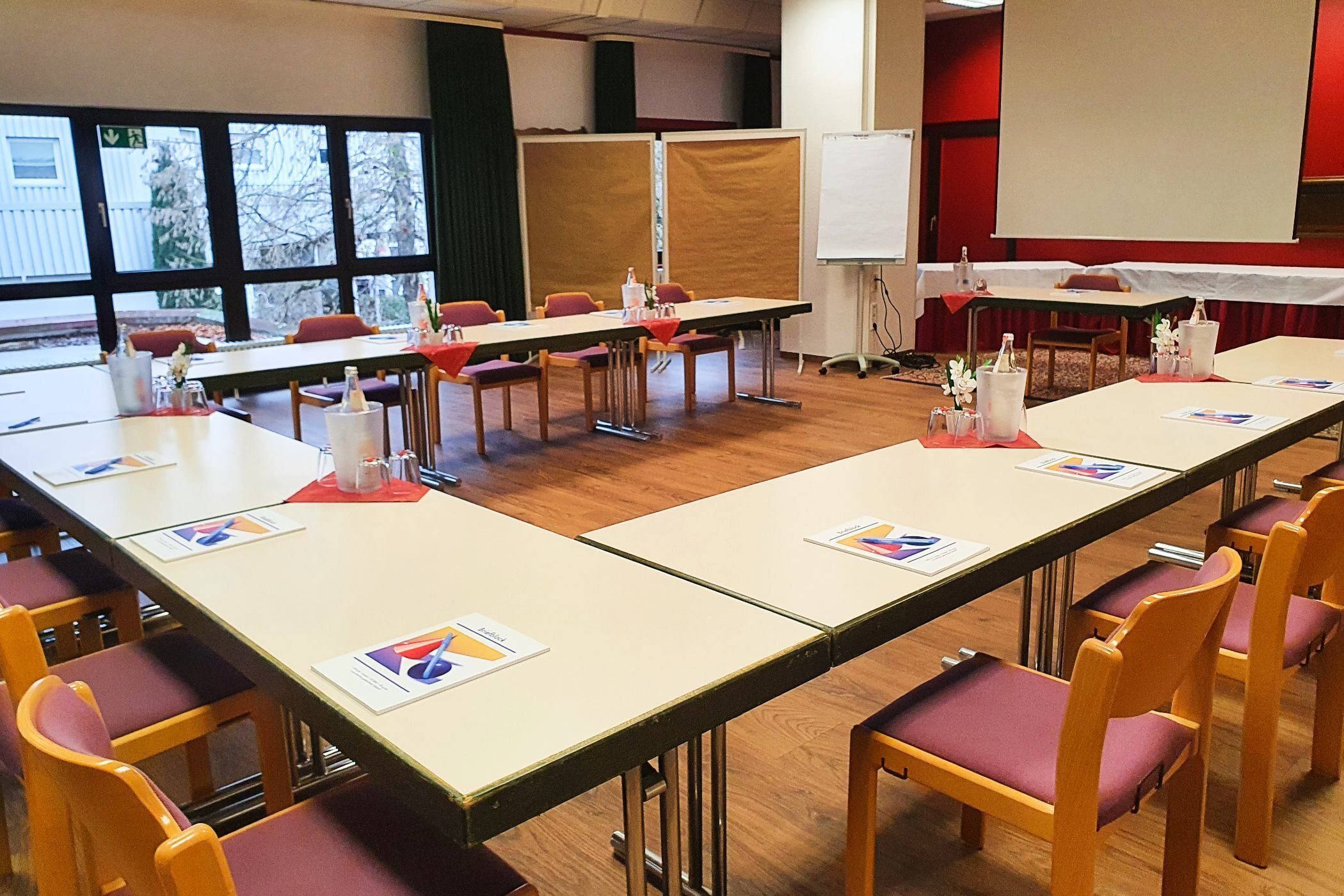 Un salón de conferencias con largas mesas, sillas y una pizarra.
