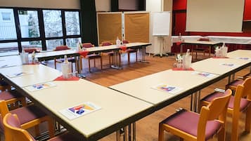 Un salón de conferencias con largas mesas, sillas y una pizarra.