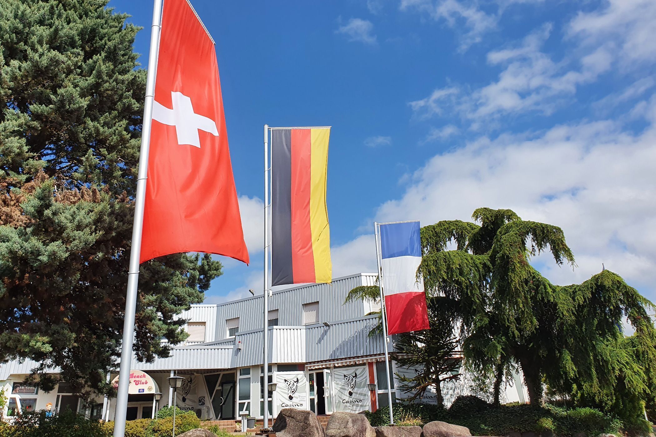 A building with multiple flags, including the Swiss flag, and a sign for a casino.