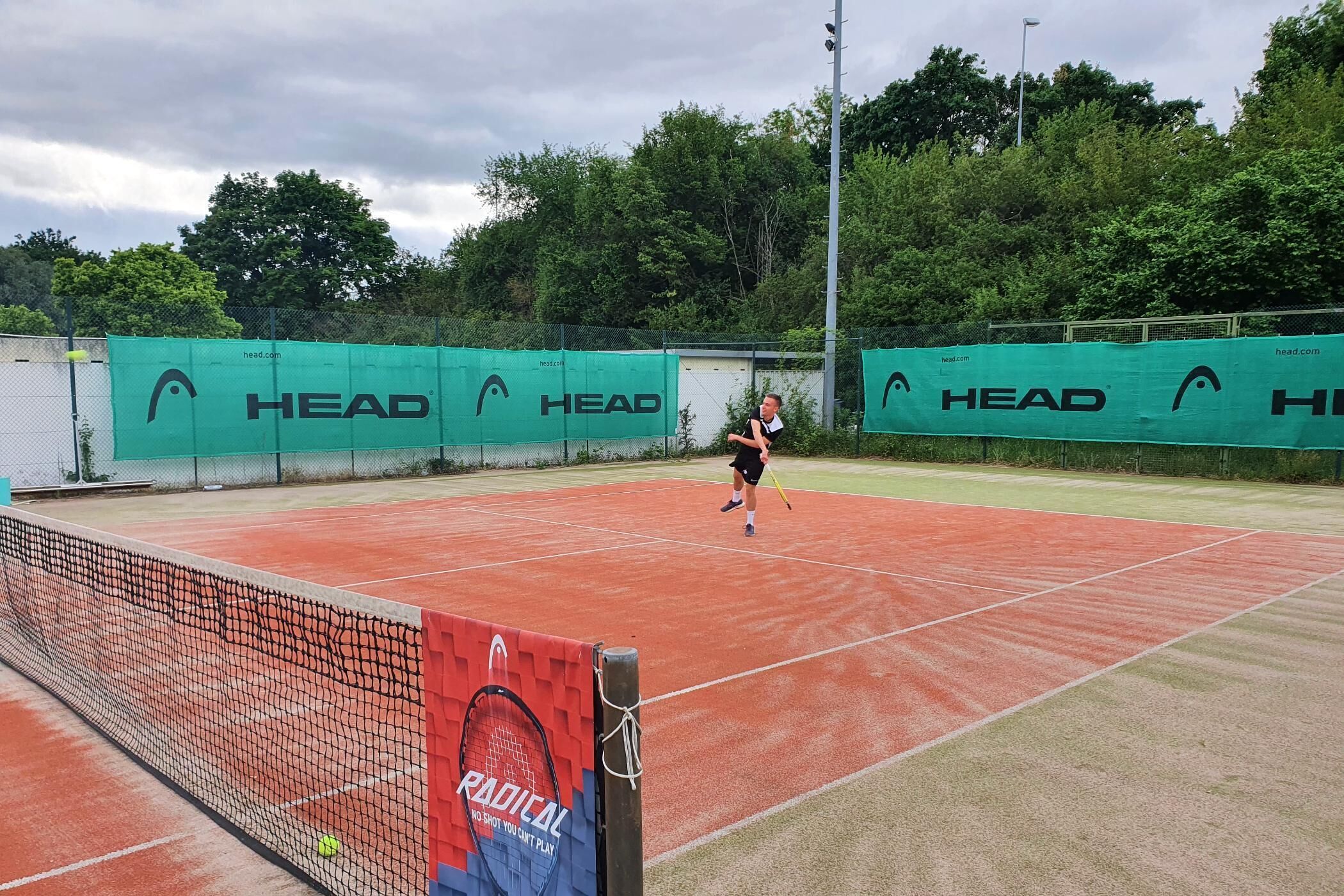 Un court de tennis avec un filet, un joueur en mouvement et une balle.