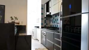 A modern kitchen with stainless steel appliances, a tiled backsplash, and a large refrigerator. - Sea Front, Front Native Forest (Florianópolis)