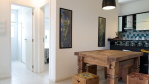 A modern kitchen with a wooden table and stools, a hanging pendant light, and a tiled backsplash. - Sea Front, Front Native Forest (Florianópolis)