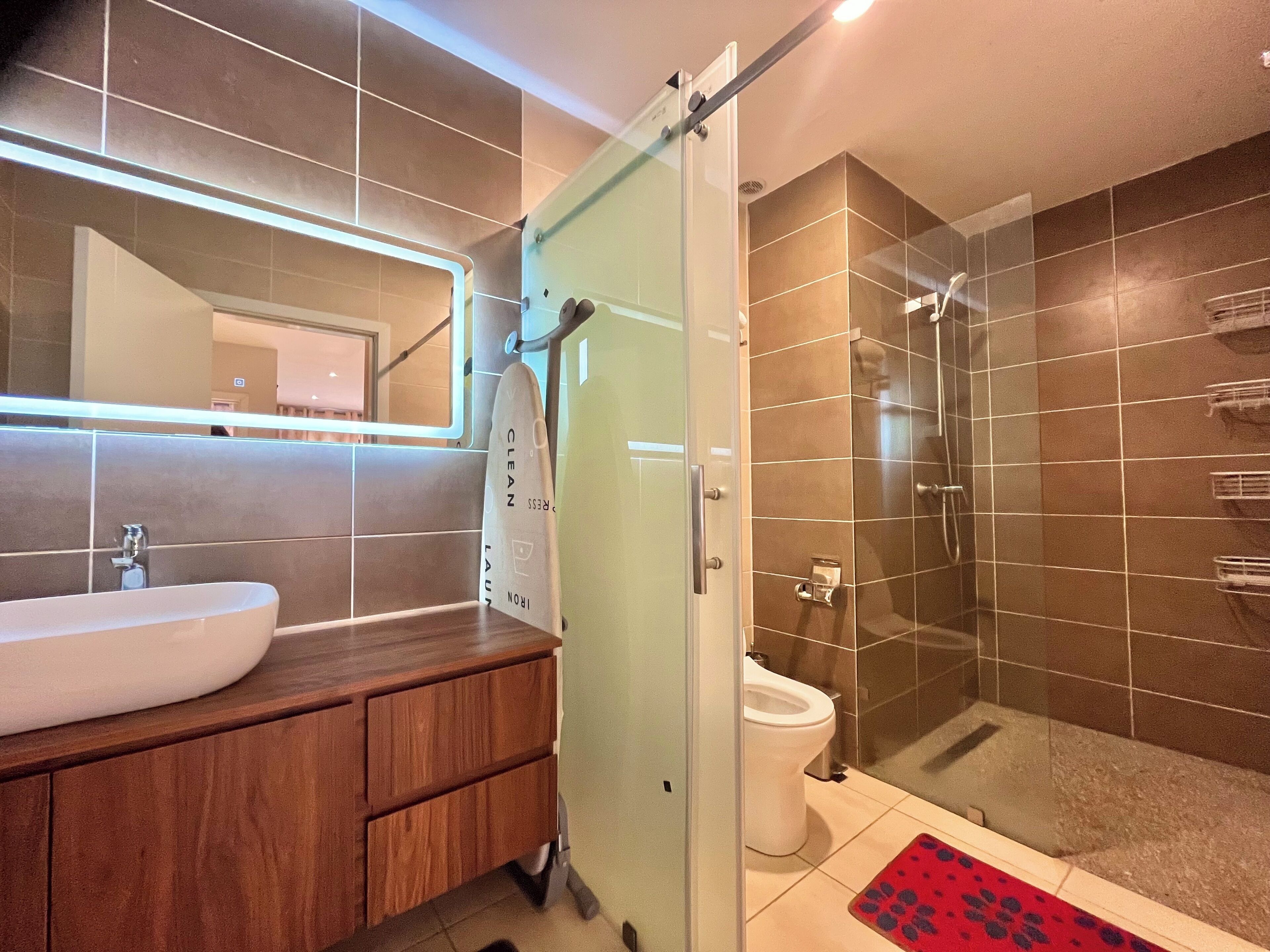 A modern bathroom with a glass shower enclosure, a white sink, and a wooden vanity.