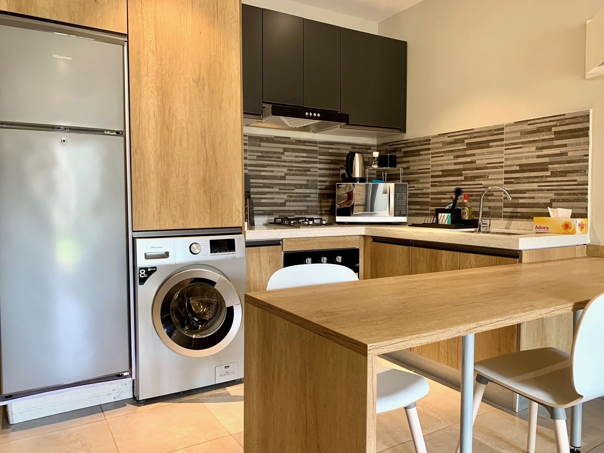 A modern kitchen with a built-in washer, a microwave, and a sink.
