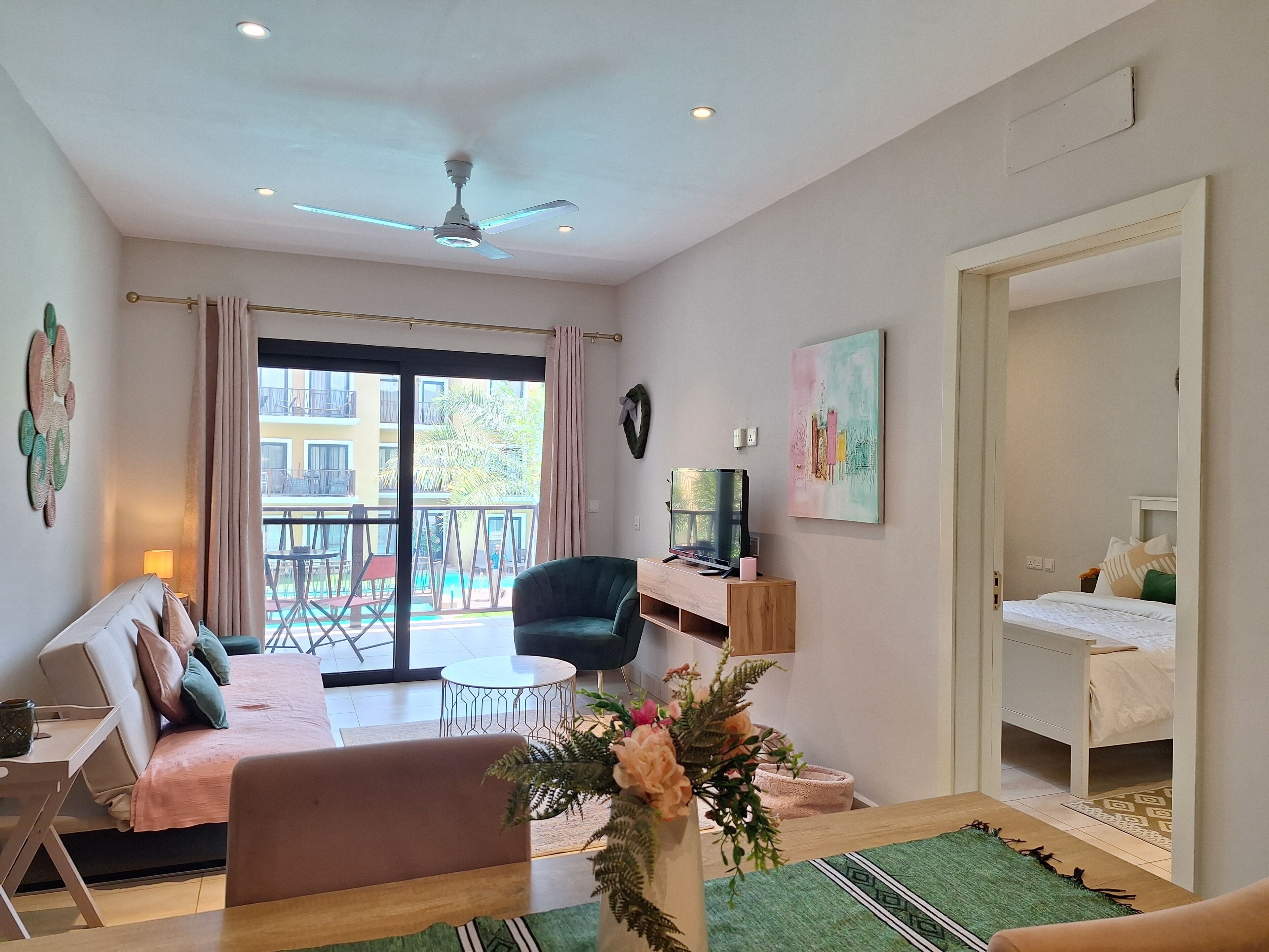 Una sala de estar moderna con un sofá, una mesa de centro, un televisor y un balcón con mobiliario exterior.