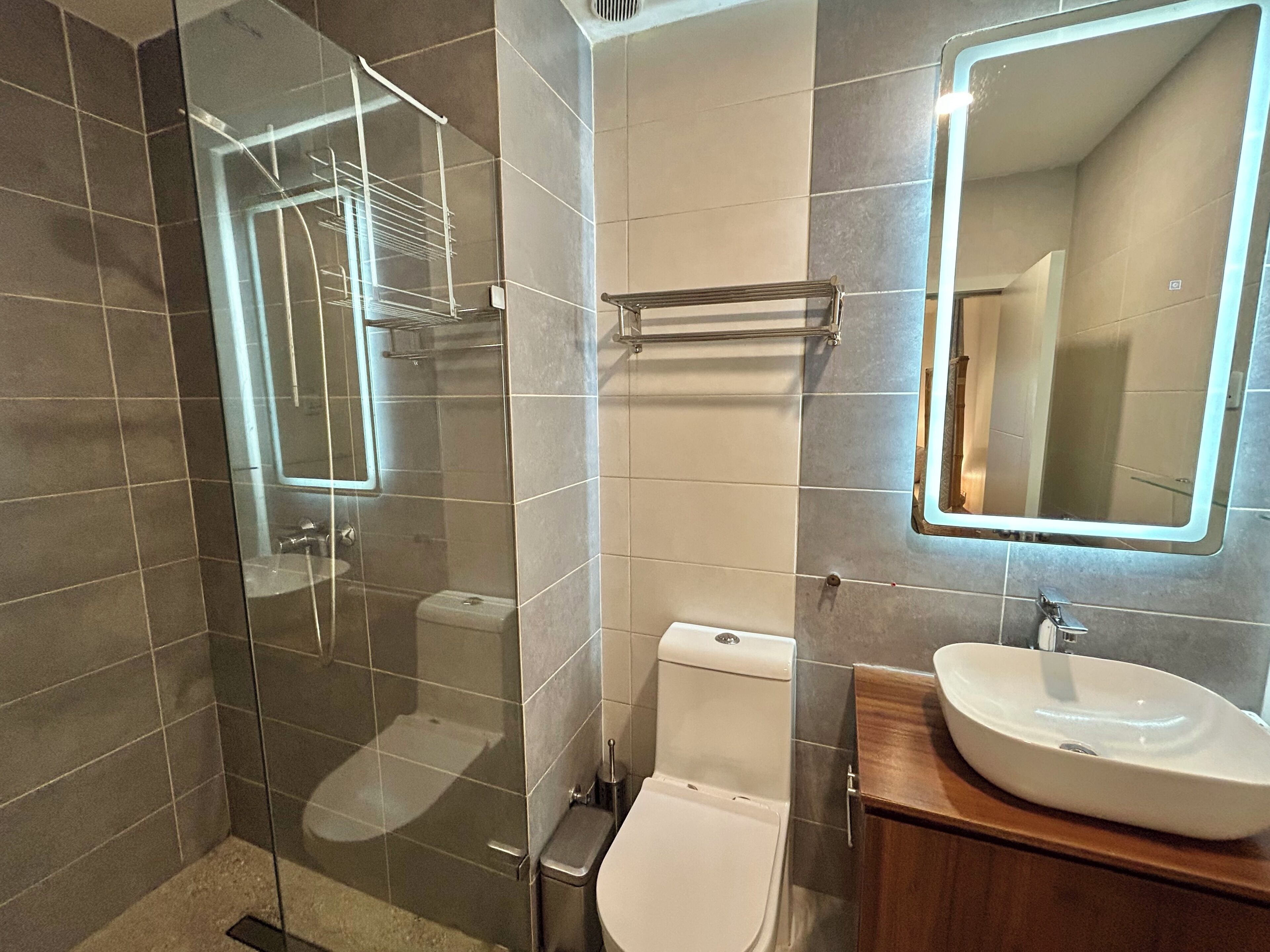 Ein modernes Badezimmer mit Duschkabine aus Glas, Toilette und Waschbecken mit Spiegel.