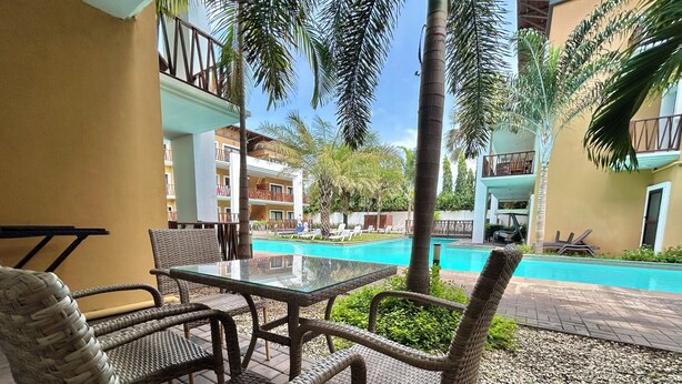 A poolside area with wicker furniture and a clear view of a swimming pool. - Forest View Apartments (Serrekunda)