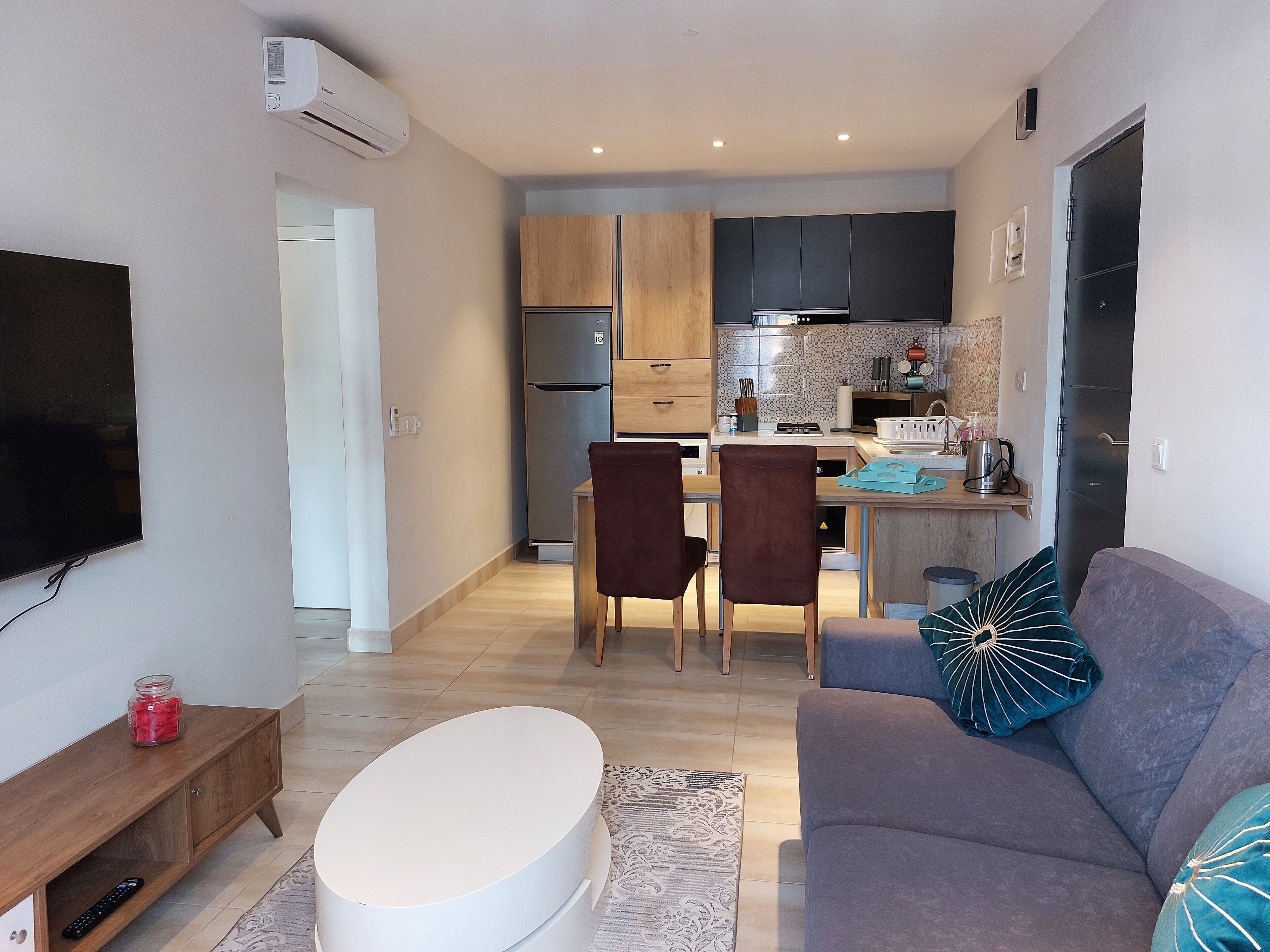 A compact living space with a dining area, kitchenette, and a seating area with a sofa and chairs.
