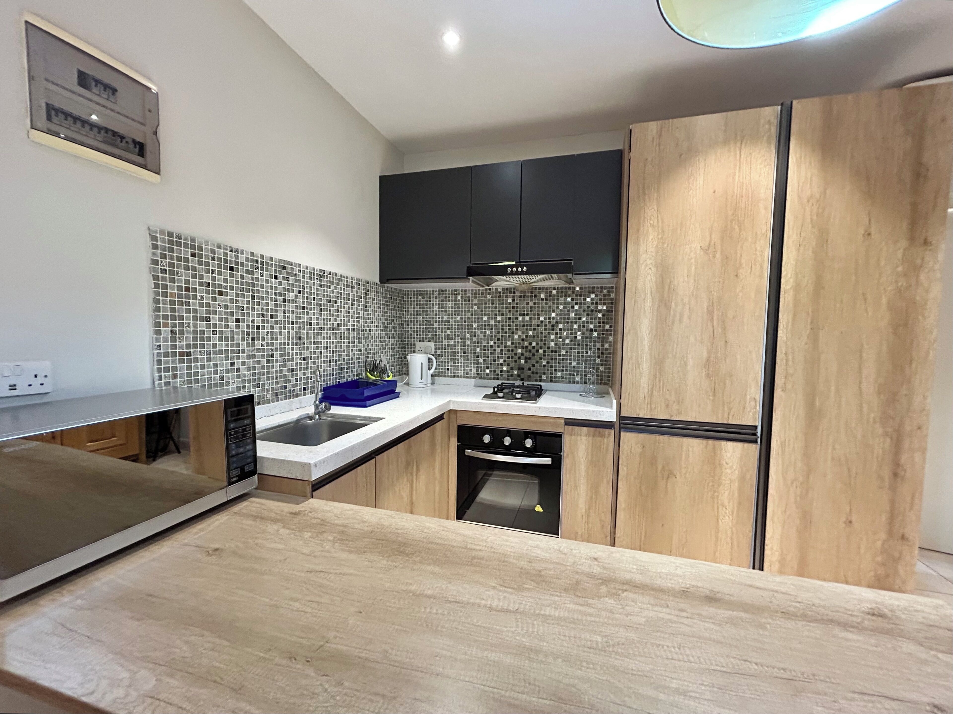 A modern kitchen with a wooden countertop, a sink, a stove, and a microwave.