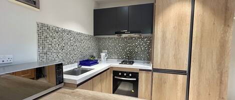 A modern kitchen with a wooden countertop, a sink, a stove, and a microwave.