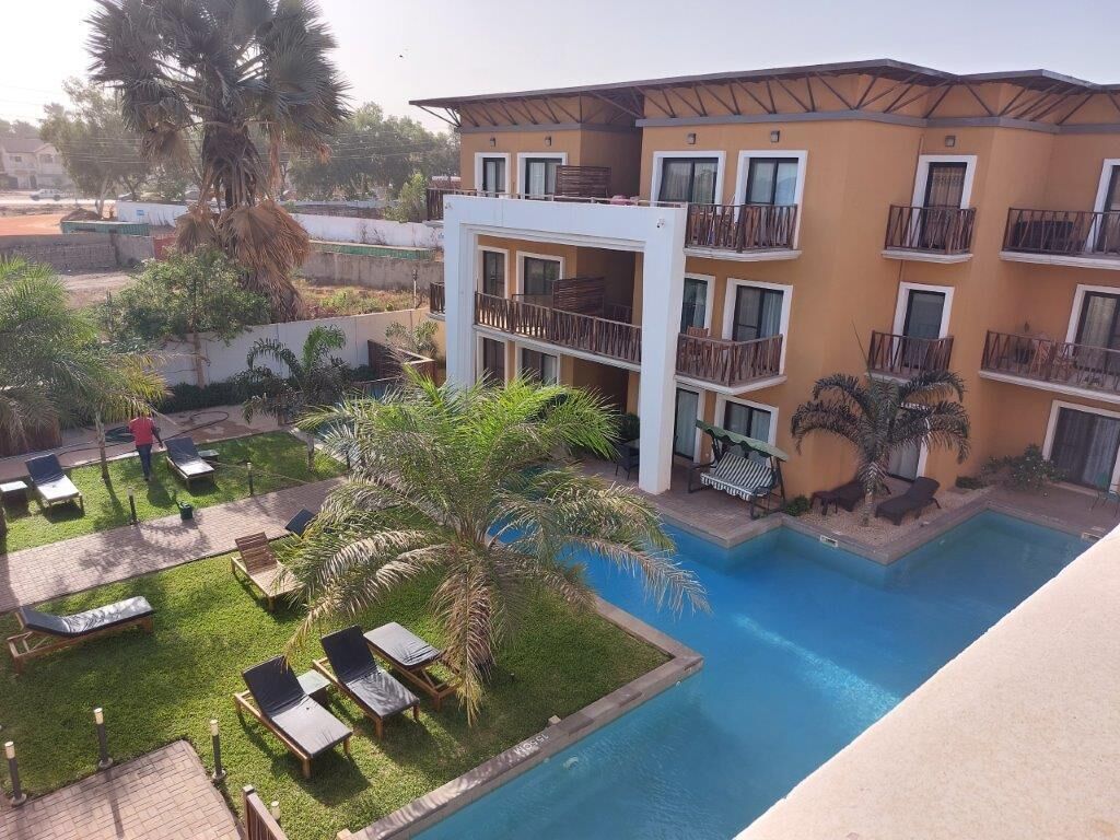 A hotel with a swimming pool, multiple balconies, and outdoor seating areas.