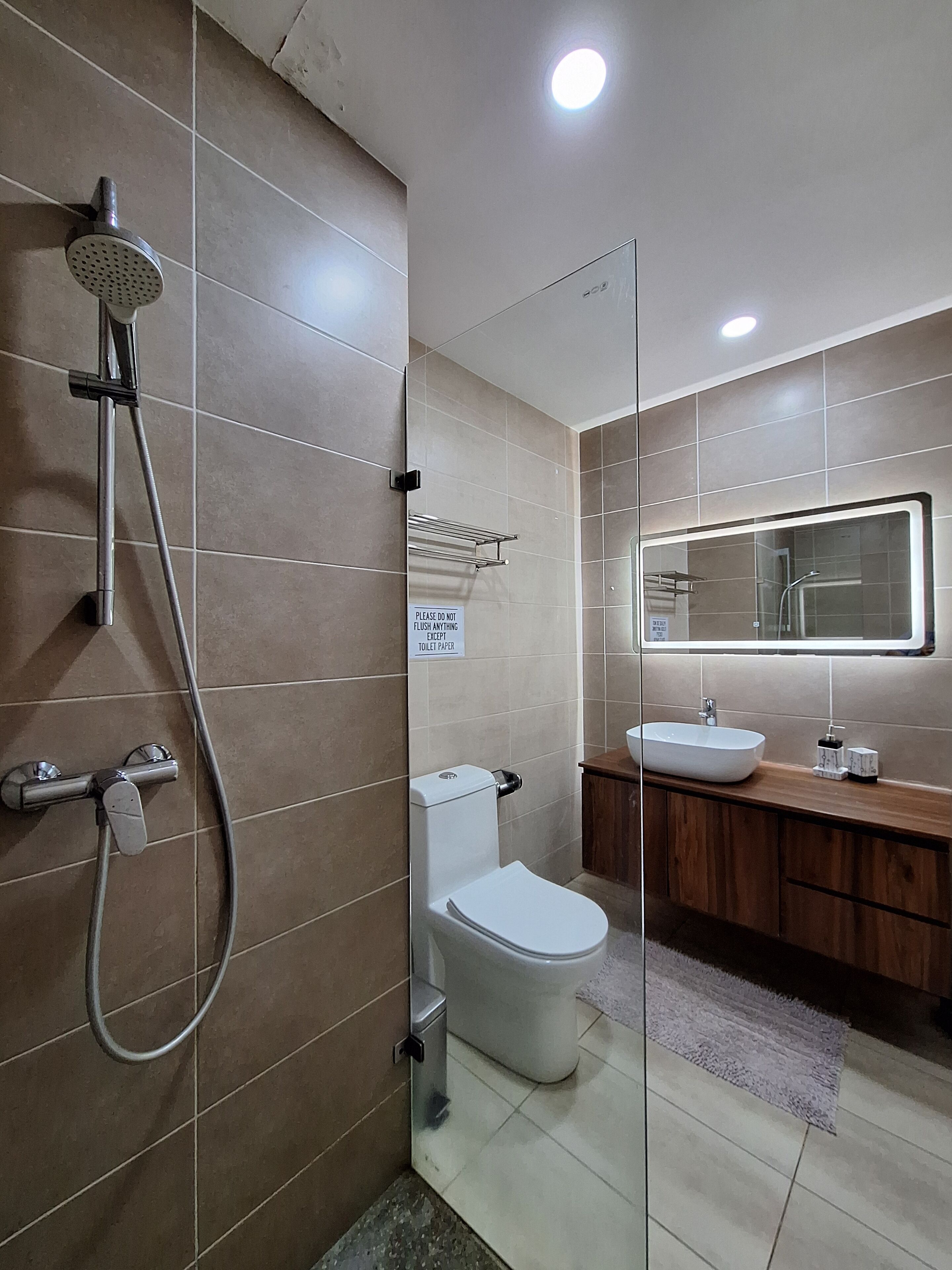A modern bathroom with a glass shower enclosure, a toilet, and a vanity with a sink.