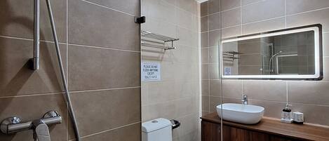 A modern bathroom with a glass shower enclosure, a toilet, and a vanity with a sink.