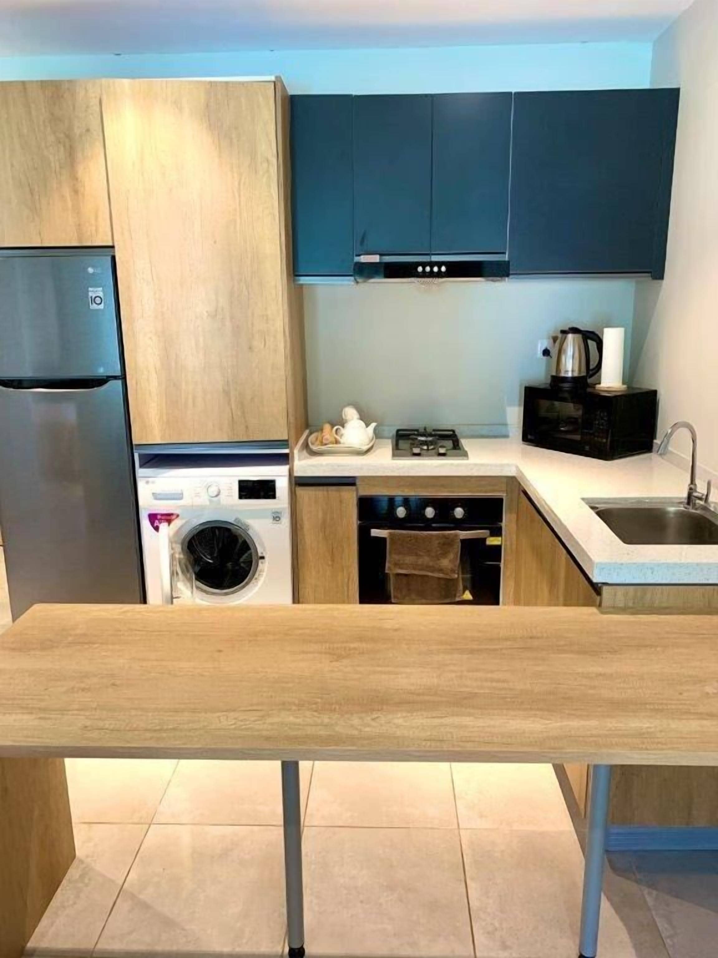 A compact kitchen with a built-in washing machine, a microwave, and a gas stove.