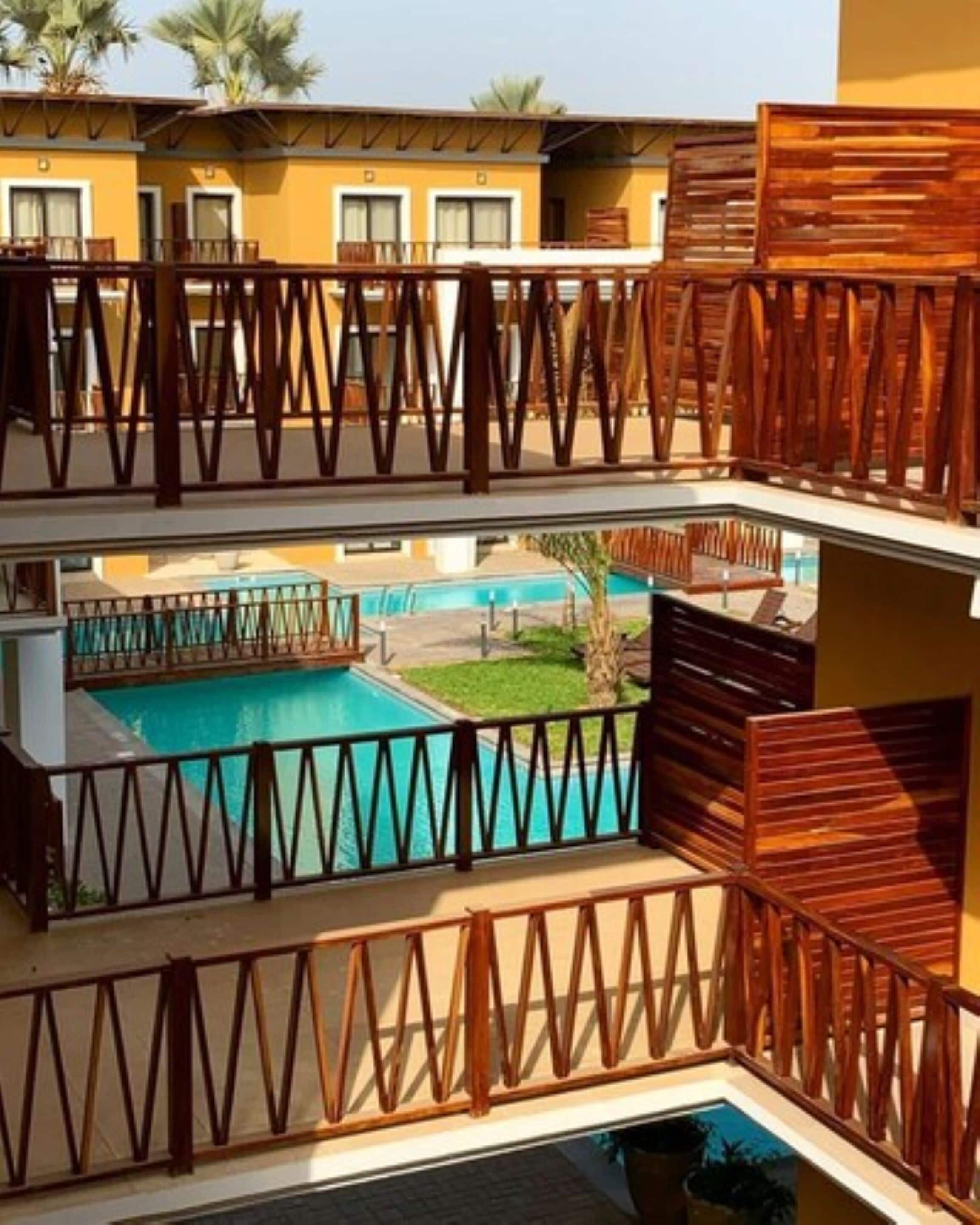 A hotel with a pool area, wooden railings, and a view of other hotel buildings.