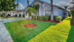 A single-story house with a well-maintained lawn, palm trees, and a clear sky. - NEW LISTING Stunning Villa - Amazing Value - Lake Berkley (Kissimmee)