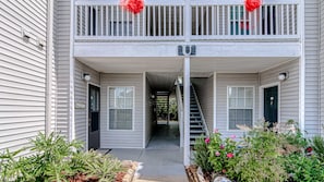 Stylish two-story residence with a covered entrance and staircase, set amidst lush greenery.