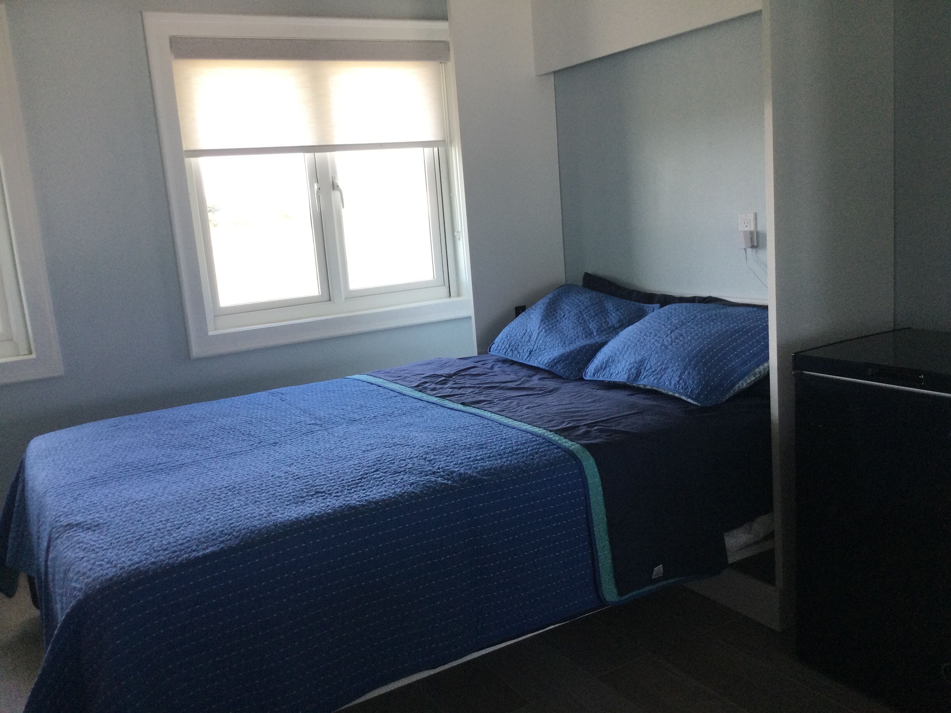 Ein Schlafzimmer mit Bett, Fenster und Kommode.
