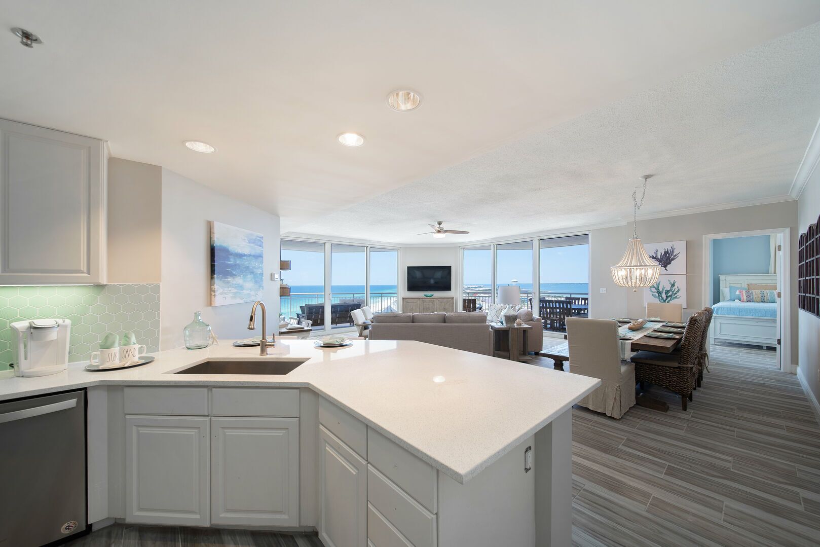 A modern kitchen with a large island, a dining area with a view, and a living room with a balcony overlooking the ocean.