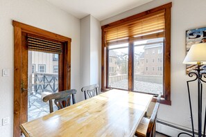 Enjoy meals in this dining area with a table and chairs, adjacent to a window with a view of a building and balcony.