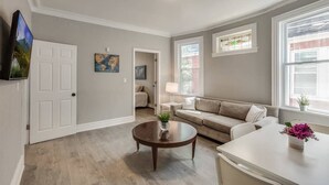 A living room with a sofa, coffee table, and a TV mounted on the wall.