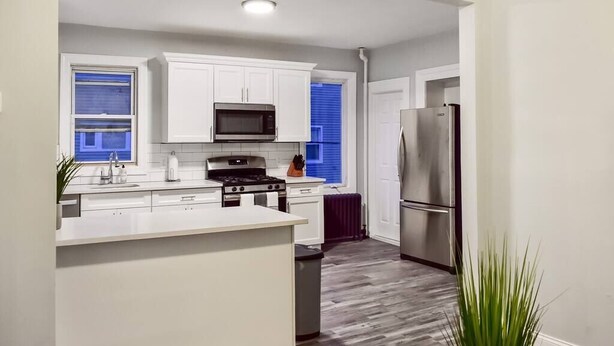 A modern kitchen with white cabinetry, stainless steel appliances, and a central island.