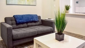 A modern living room with a grey sofa, a white coffee table, and a potted plant.
