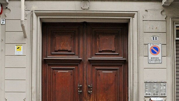 A large wooden double door with a metal handle, flanked by a small window with shutters and a sign indicating a no parking zone. - La Casa di Mattoni by Wonderful Italy (Torino)