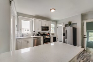 A modern kitchen with white cabinetry, stainless steel appliances, and a large island.
