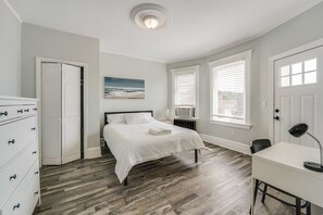 Une chambre à coucher avec un lit, une commode, un bureau et des fenêtres.