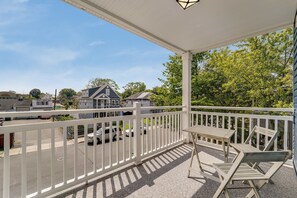 A covered outdoor area with a white railing, a table, and two chairs.