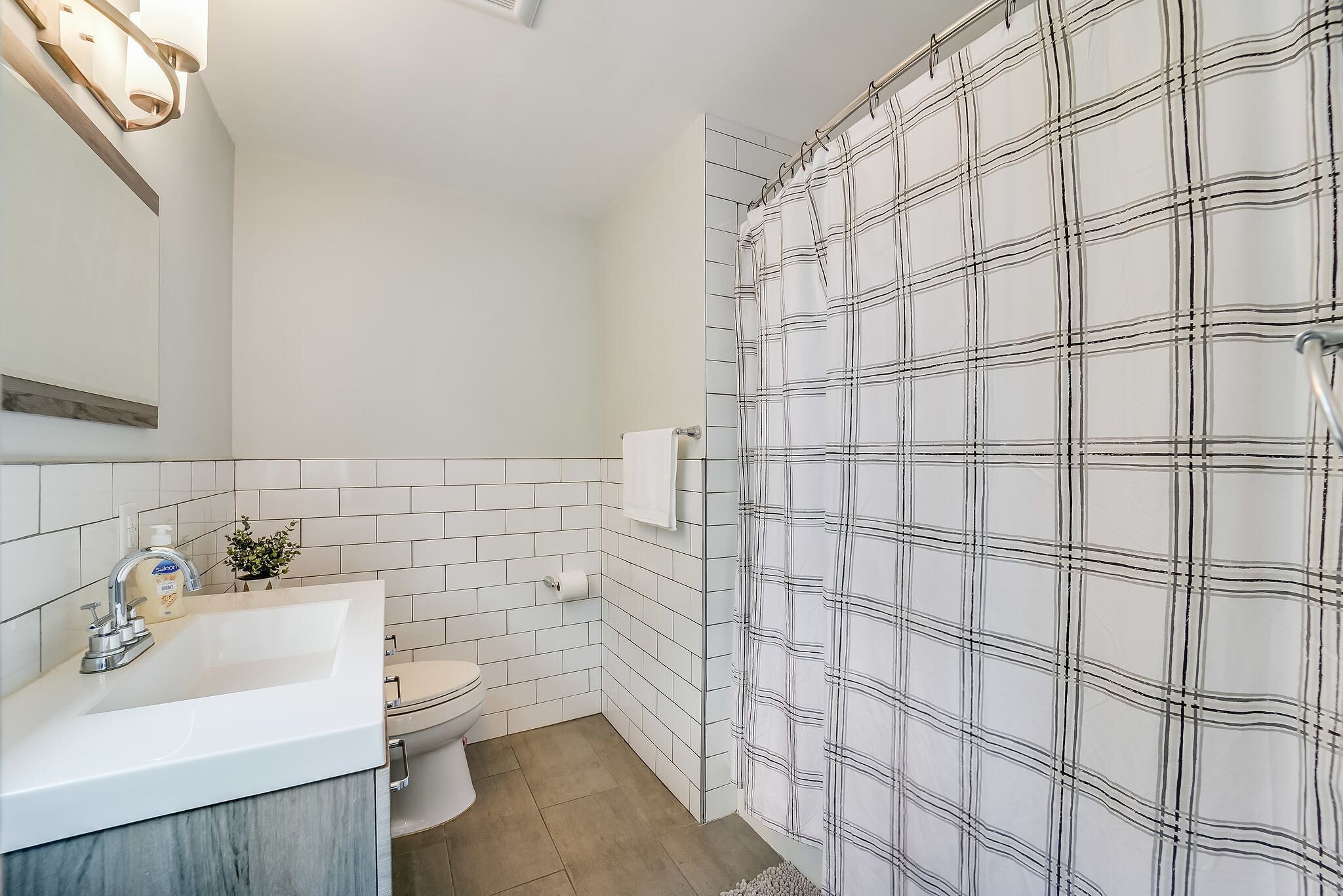 Une salle de bain avec un lavabo blanc, des toilettes et un espace douche agrémenté d’un rideau à motifs.