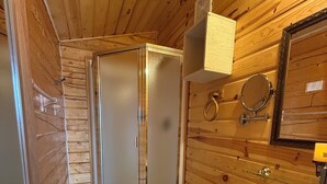 A wooden-paneled bathroom with a toilet, sink, and shower. - Earthsong Lodge -Two Room Cabin (Healy)