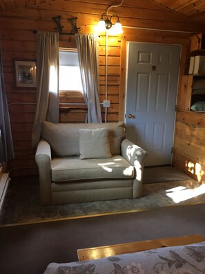 A cozy room with a sofa, curtains, a door, and a small rug.
