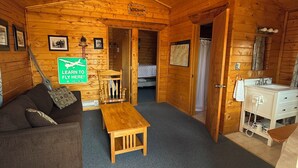 L’intérieur d’un chalet confortable, avec un plafond en bois, un canapé, une petite table, un bureau et un lit.