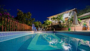 Una piscina con borde de azulejos, rodeada por una valla de madera y plantas en macetas.