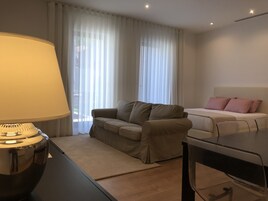 Una habitación de hotel moderna con sofá, cama, escritorio y lámpara.