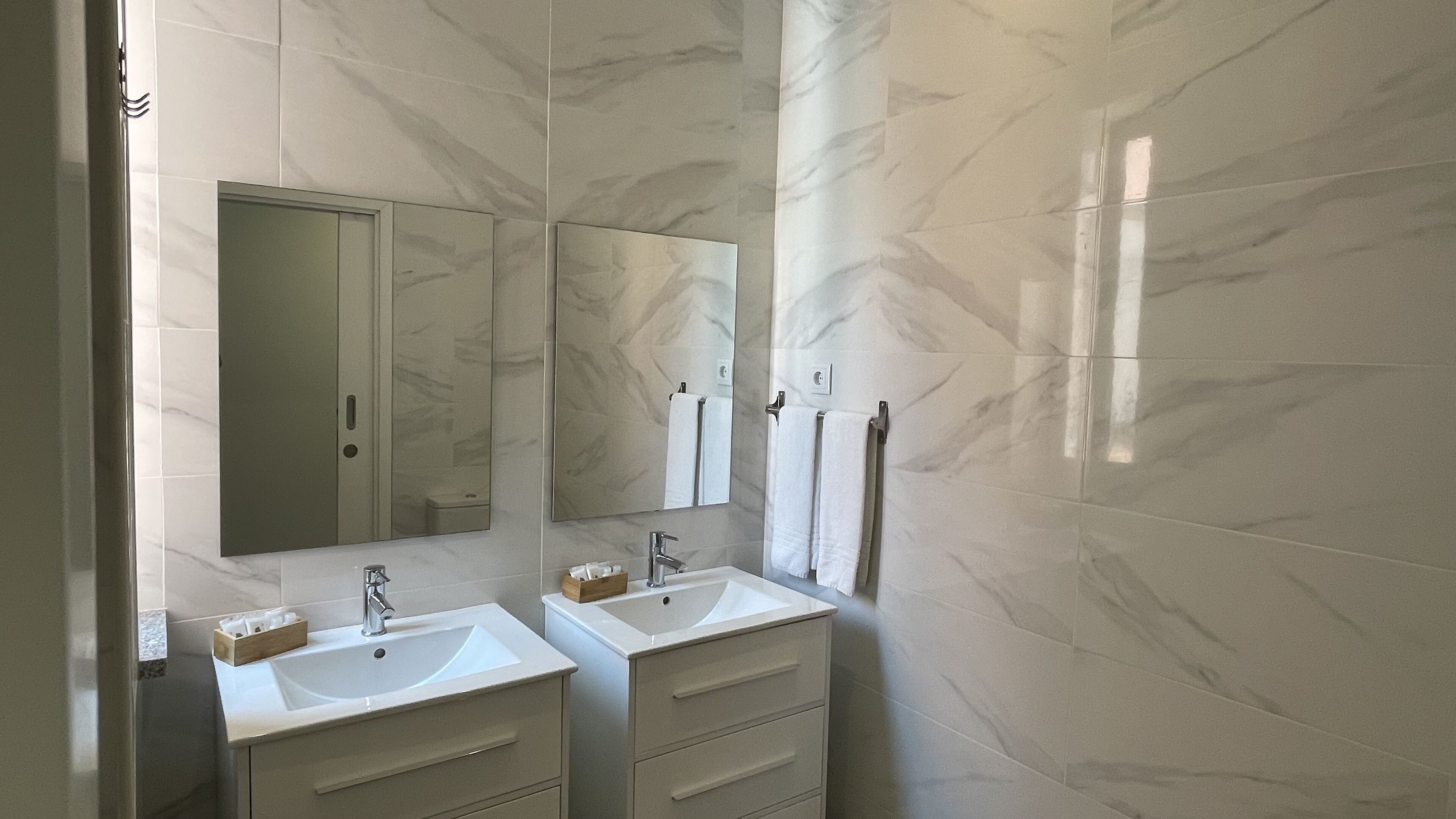 A bathroom with two sinks, a mirror, and marble walls.