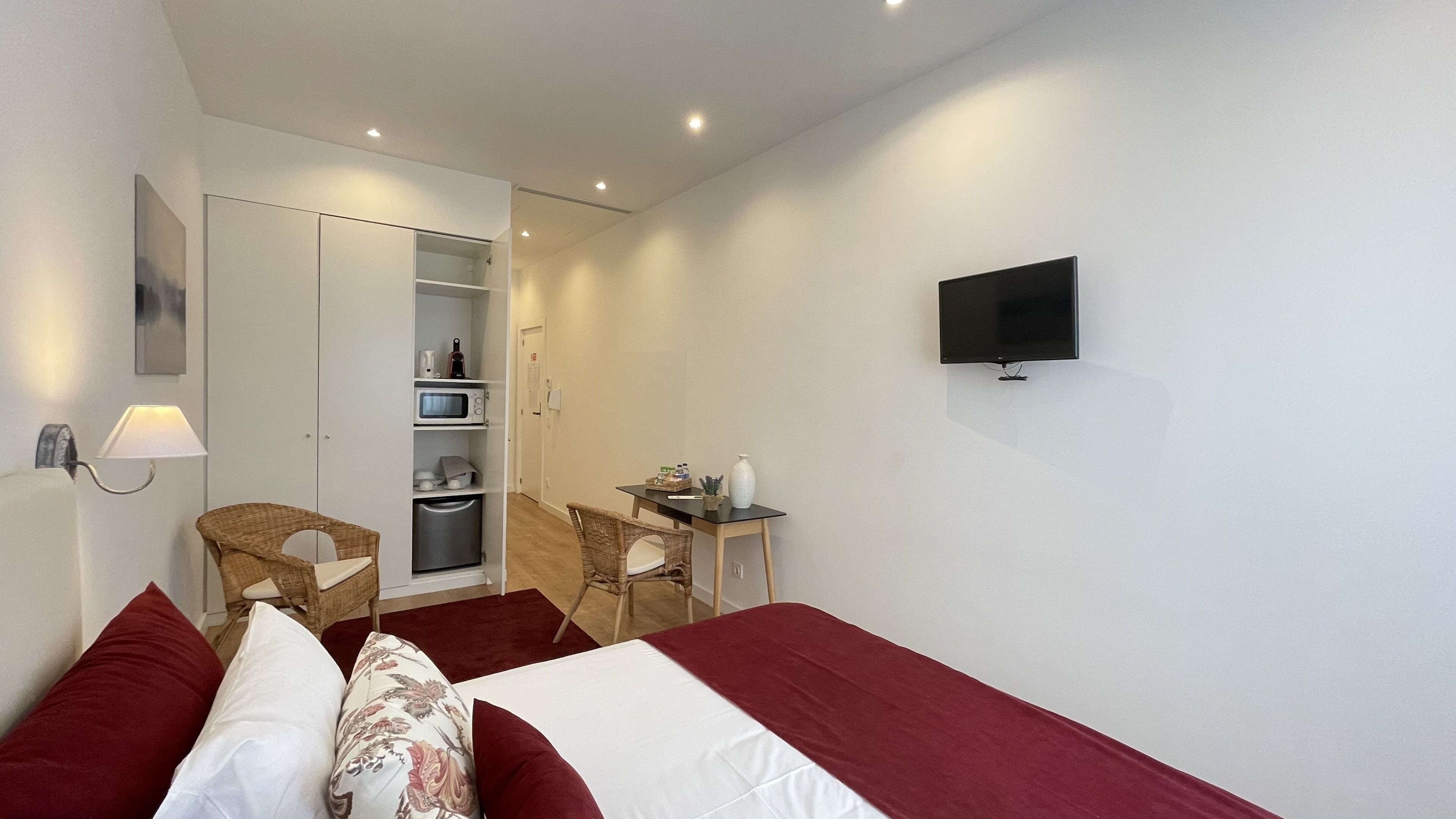 Een hotelkamer met een bed, een bureau, een stoel, een televisie en een kledingkast.