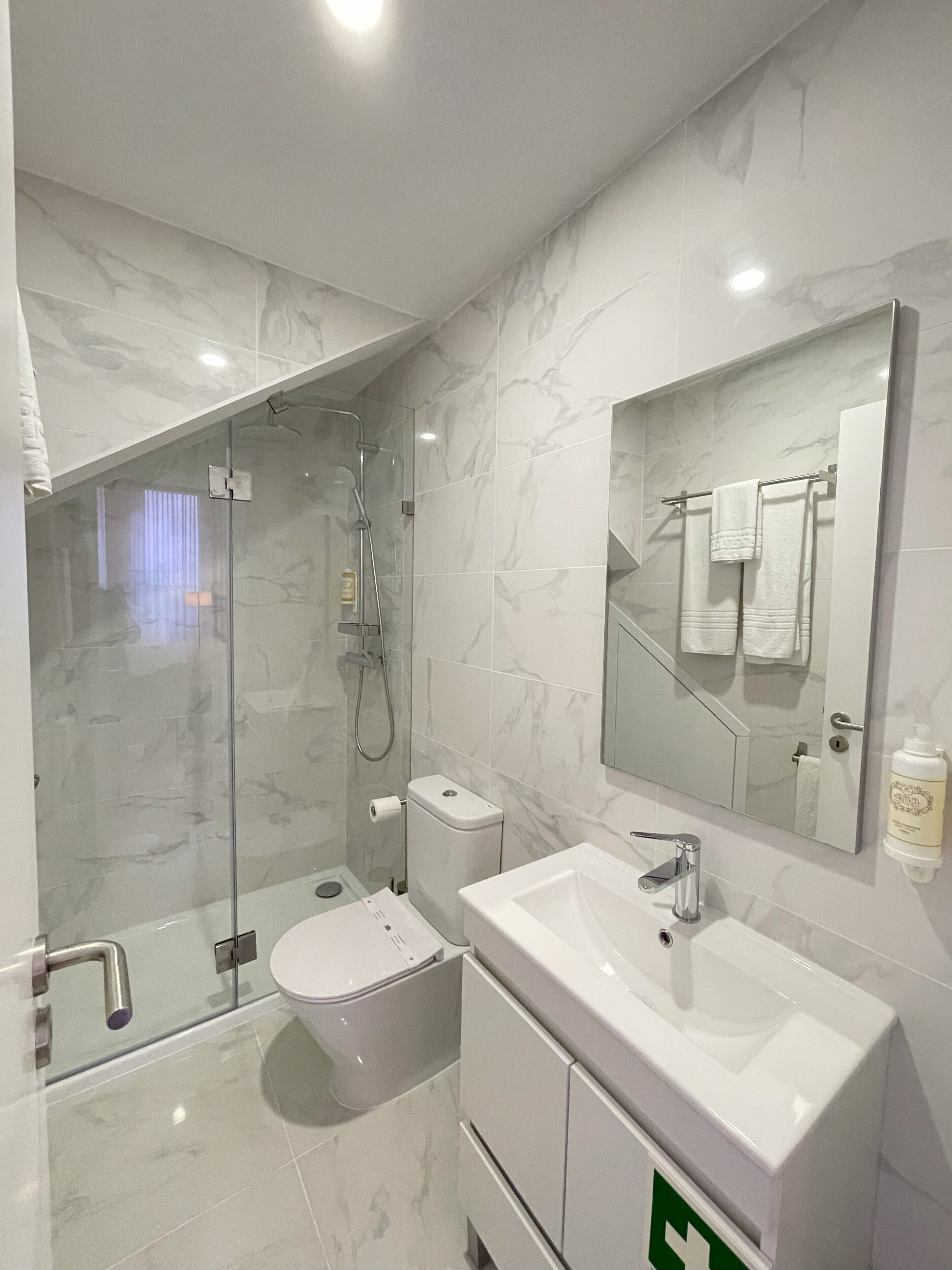Une salle de bain moderne avec une douche à parois de verre, des toilettes et un lavabo avec un miroir au-dessus.