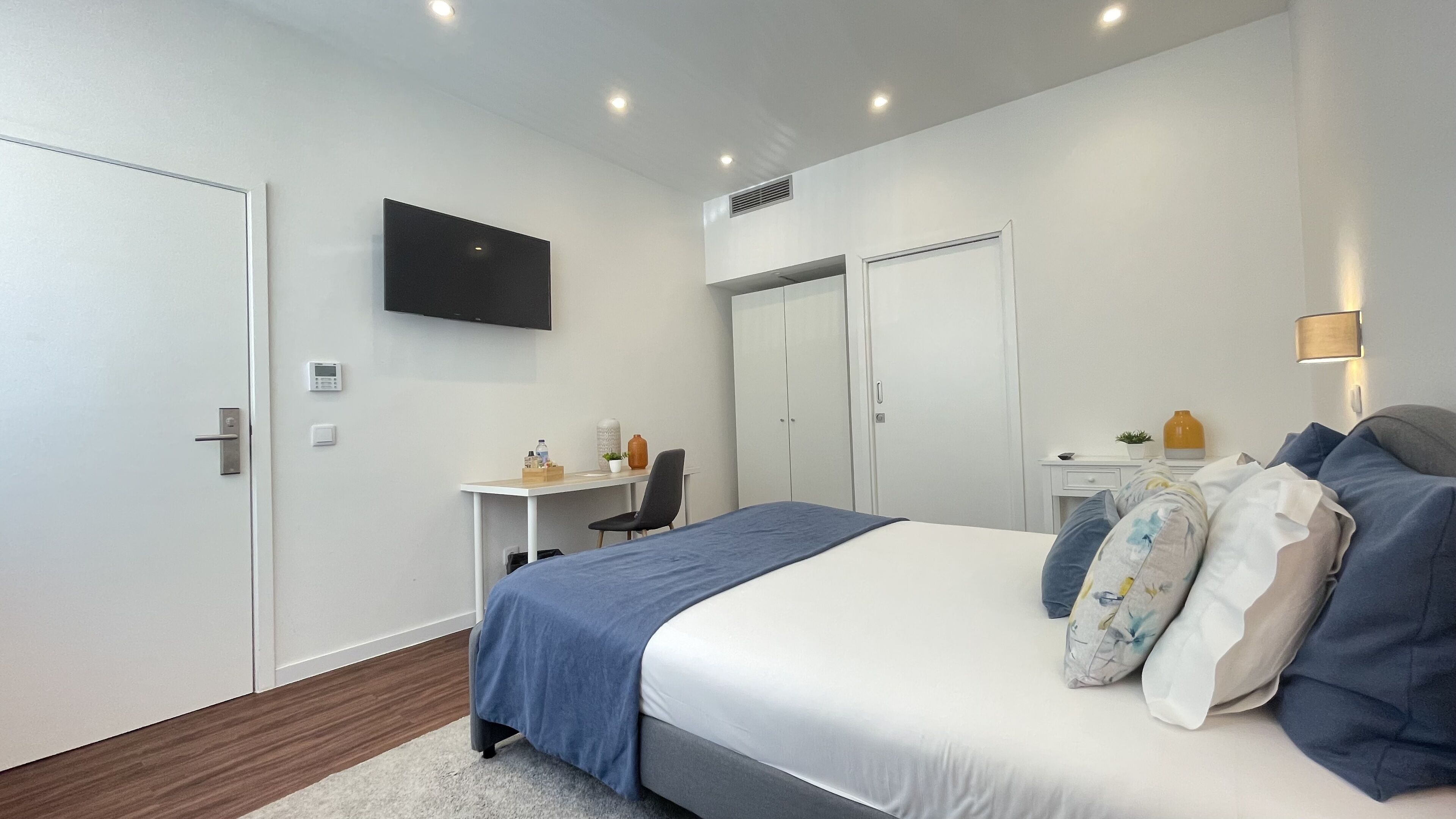 Une chambre à coucher moderne avec un lit, un bureau et un téléviseur.
