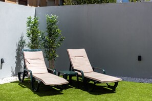Two lounge chairs with cushions, a small potted plant, and a white wall. - MyTrip Porto (Matosinhos)