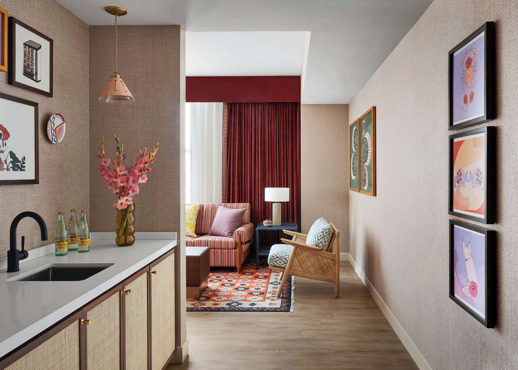 A modern living room with a sofa, a chair, a rug, and framed artwork on the walls.
