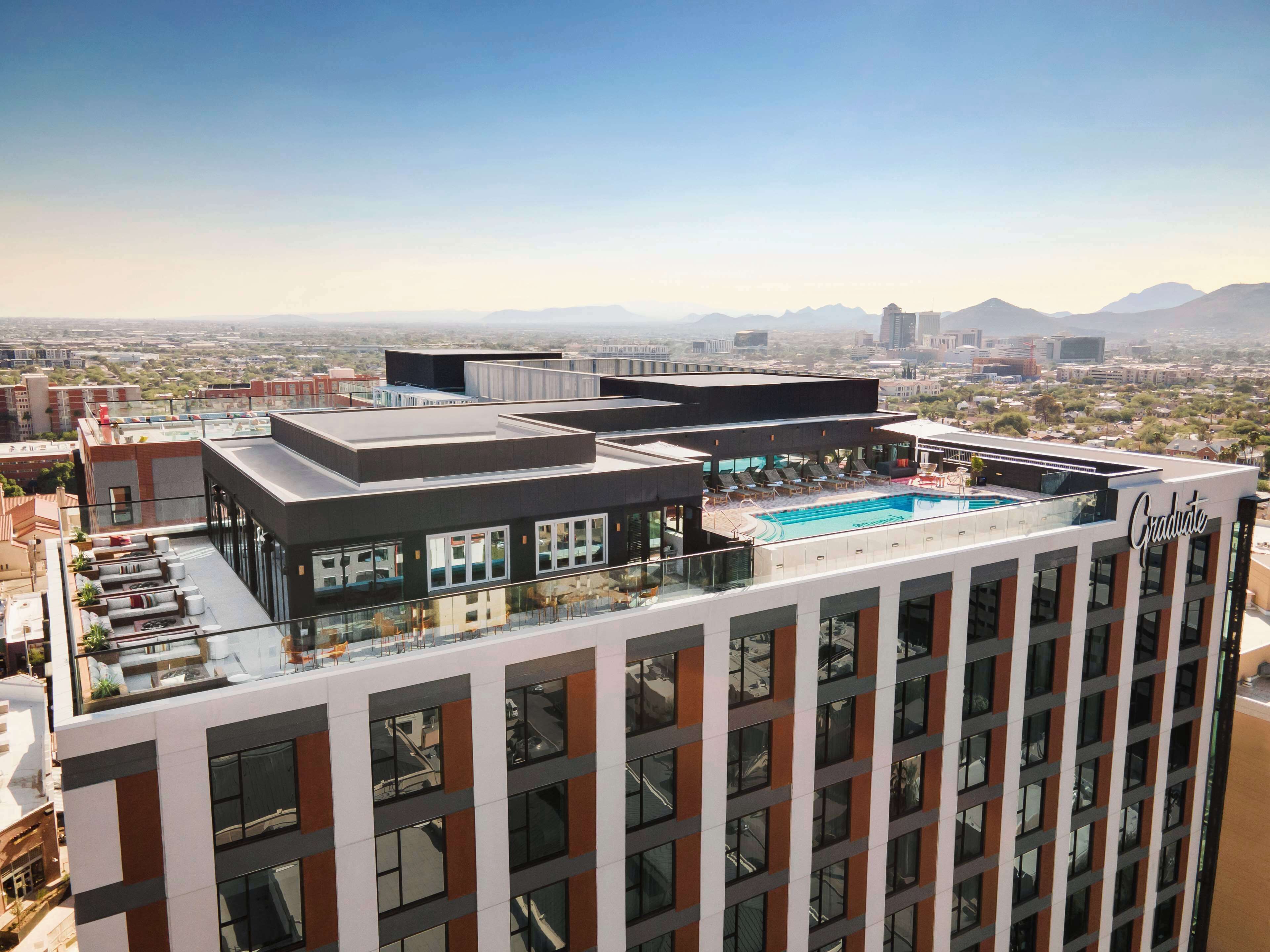 Un hotel moderno con piscina en la azotea, amplias ventanas y vistas a la ciudad.