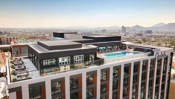 Un hotel moderno con piscina en la azotea, amplias ventanas y vistas a la ciudad.