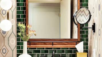 A bathroom with a large mirror, green tiled backsplash, and a white sink.