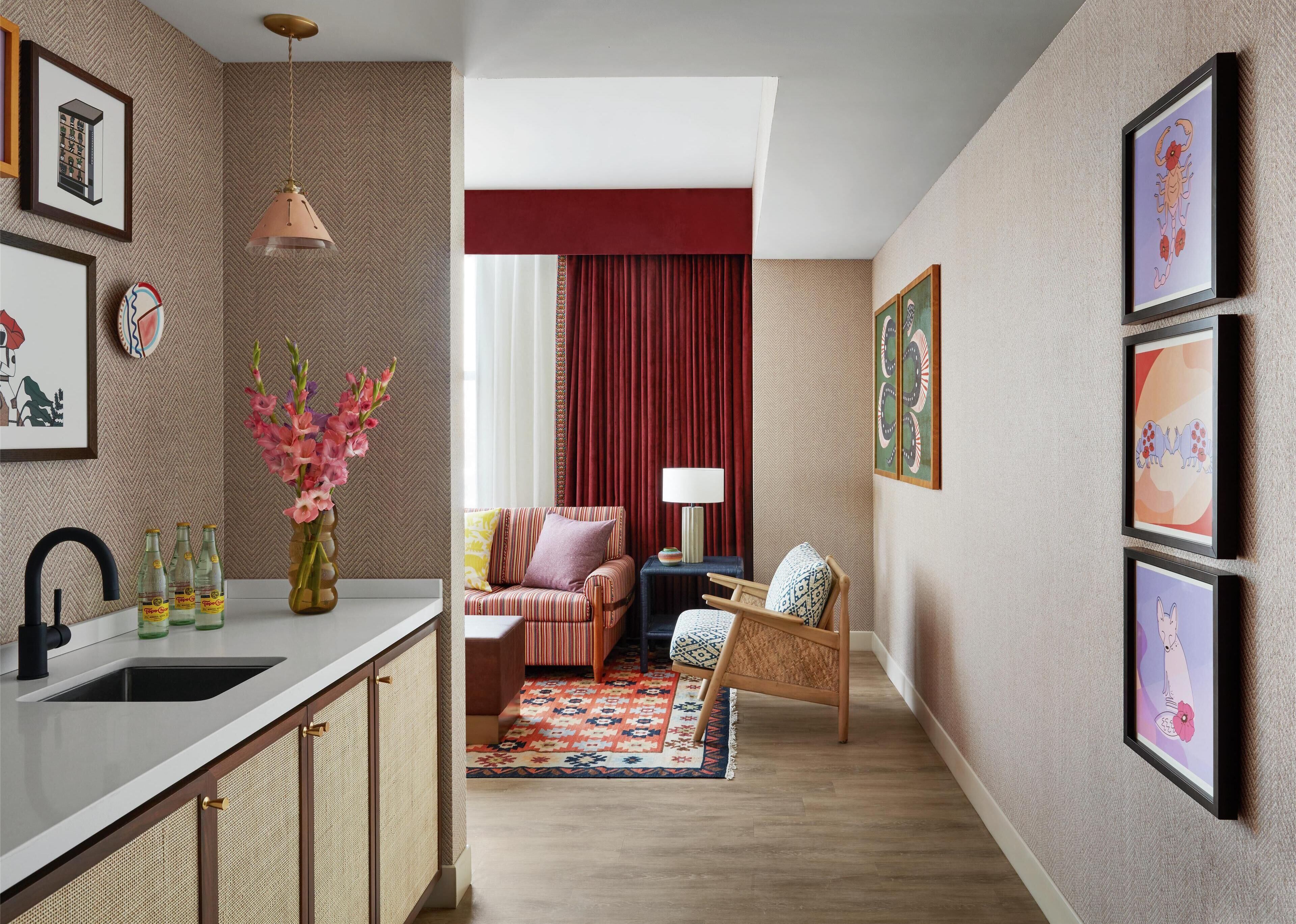 Un salon moderne avec un canapé, un tapis à motifs et un coin repas comprenant un évier et des bouteilles.