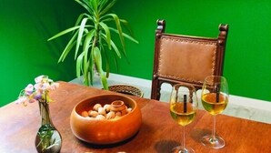 A dining table with a bowl of nuts, a vase with flowers, and two glasses of wine. - Ferienwohnung Albert, 2 Schlafzimmer, 90 Quadratmeter (Hauenstein)